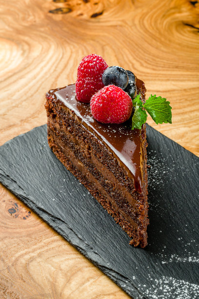 巧克力蛋糕片与覆盆子，蓝莓和薄荷宏观近距离垂直放在木桌上图片下载