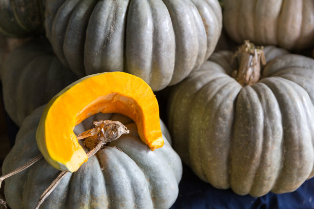 南瓜和切好的南瓜站在市场的摊位上图片下载