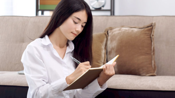 年轻的亚洲妇女写在笔记本纸在家里的办公室图片下载
