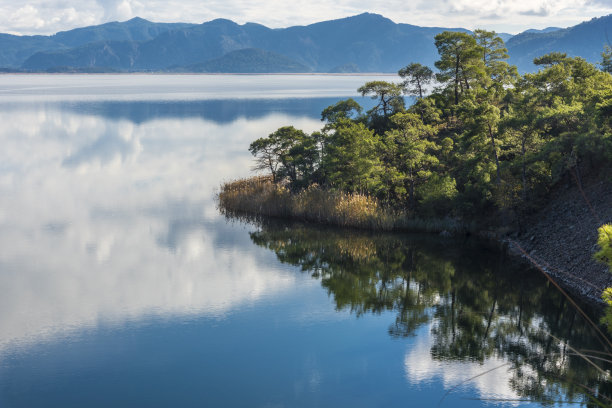 湖边的森林和水面上天空的云的倒影图片下载