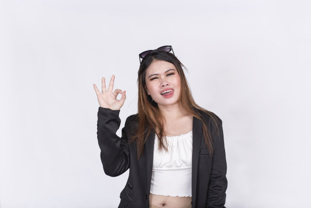 一个有魅力的亚洲女人与活泼的个性做了一个Ok的手势，同时伸出她的舌头。孤立在白色背景上。图片下载