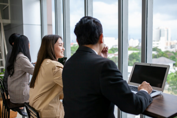 亚洲商务团队的男女同事在工作中聊天，用笔记本电脑分享想法，快乐的同事在办公室用电脑一起工作。图片下载