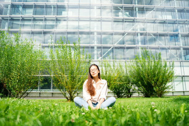年轻的越南女人坐在写字楼附近的草地上做梦图片下载