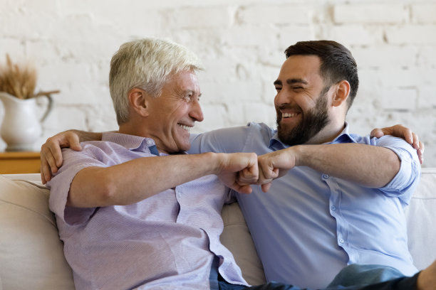 快乐的老人把儿子拳头碰坐在沙发上图片下载