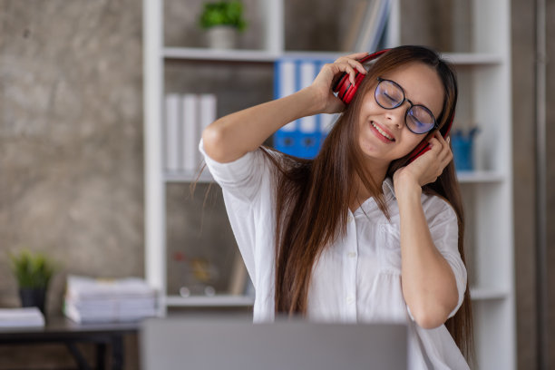 年轻美丽的亚洲女性女孩在休闲穿着放松和听音乐耳机和室内工作图片下载