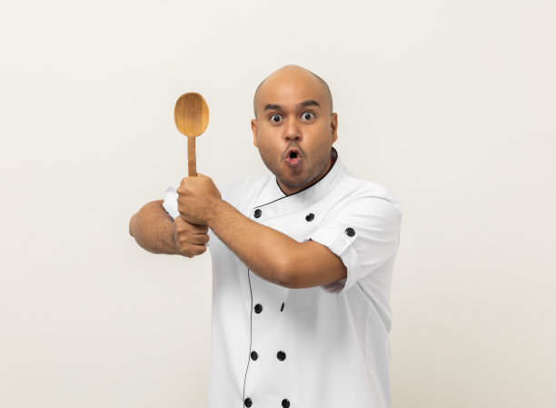 年轻英俊的亚洲男子厨师在统一的勺子器皿烹饪在厨房的各种手势动作上孤立的背景。印度男子职业厨师餐厅和酒店。图片下载