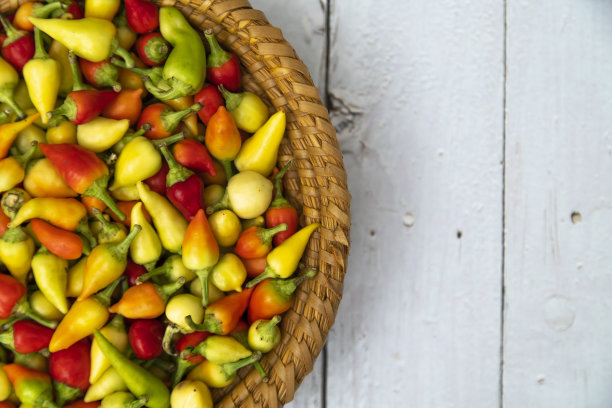 红辣椒和青椒放在一个碗里，背景是木头图片下载