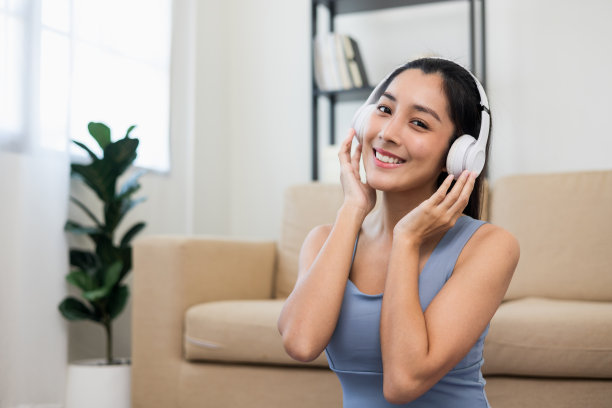 漂亮的亚洲女人穿着运动服戴上耳机听音乐放松后锻炼。喜欢运动的女性在家穿着运动服锻炼和锻炼。图片下载