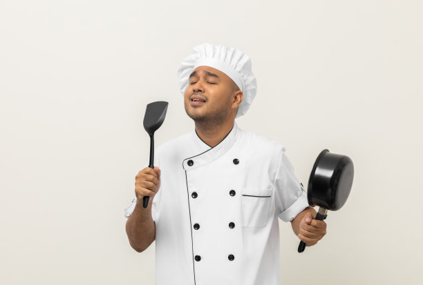超级明星唱歌厨艺大师。年轻快乐的亚洲厨师穿着制服，在孤立的白色背景下享受着歌声和舞蹈。印度男人占领餐馆和酒店。图片下载