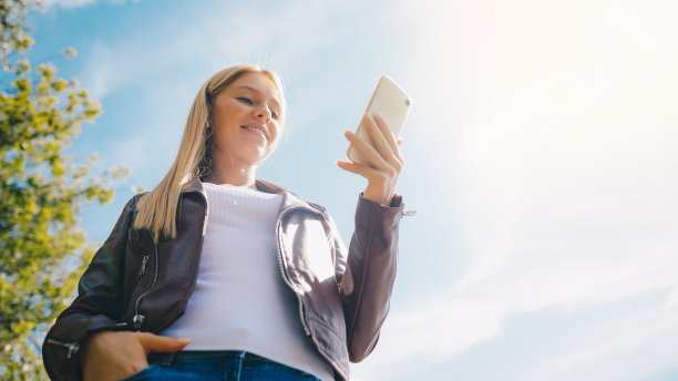 年轻微笑的女孩与移动设备，咖啡，无线耳机在公园图片下载