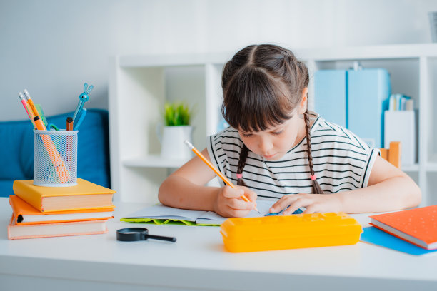 聪明集中的小7岁白人女孩孩子坐在书桌家学习远方做作业用教科书。图片下载