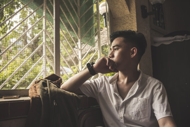 一个悲伤的亚洲男人看着外面，思考着他分手后的生活。图片下载