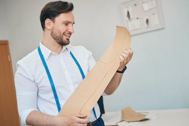 男时装设计师在缝纫车间检查一个图案图片下载