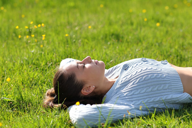 一个女人躺在山上的草地上休息图片下载