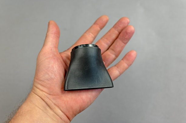 这个人拿着电吹风的集中器喷嘴。该喷嘴的设计是为了创造一个有方向的流动，丰盈的头发和按摩。灰色的背景。在室内。特写镜头。图片下载