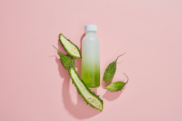 苦瓜在培养皿中的俯视图，绿叶和空白的粉红色背景图片下载