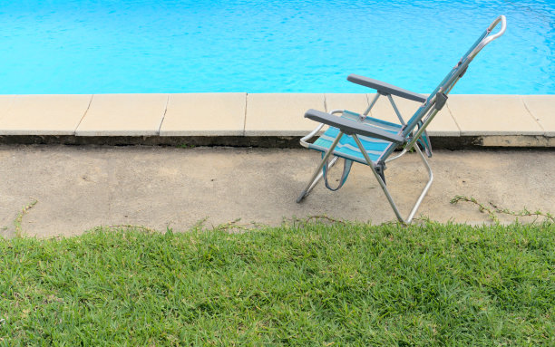蓝色折叠椅旁边的游泳池在一个非常炎热的夏天。度假休闲概念。图片下载