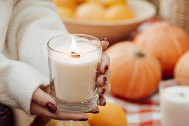 一个以南瓜为背景的女孩手中燃烧的蜡烛图片下载