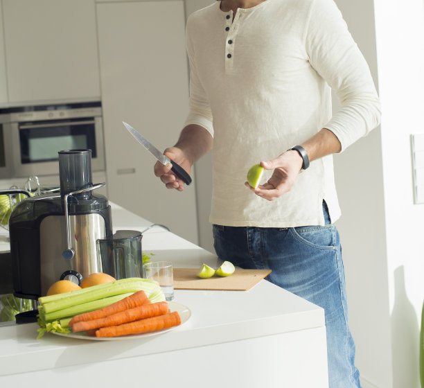 男子准备纯素新鲜果汁。年轻健康的运动男在厨房做饭，在搅拌机里切和搅拌，喝新鲜的蔬菜，新鲜的苹果。素食健康饮食理念图片下载