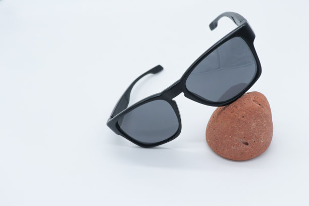 黑色方形太阳镜中性模型在白色背景与棕色石头装饰图片下载