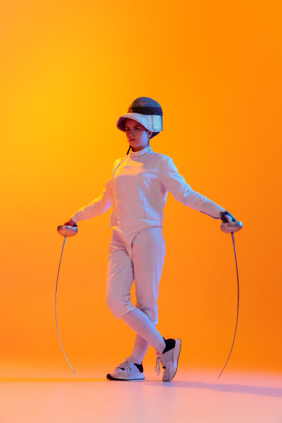 工作室拍摄的专业击剑运动员在白色击剑服和面具的行动，运动孤立在橙色的背景。体育，青年，活动，技能，图片下载