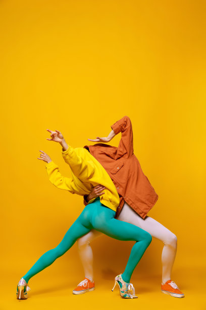 创造性的彩色肖像的男人和女人在明亮的衣服隐藏的脸摆出孤立的黄色背景。跳舞图片下载