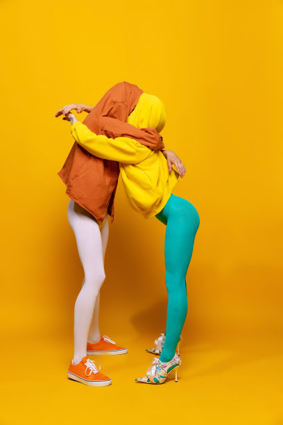 创造性的彩色肖像的男人和女人在明亮的衣服隐藏的脸摆出孤立的黄色背景。拥抱图片下载