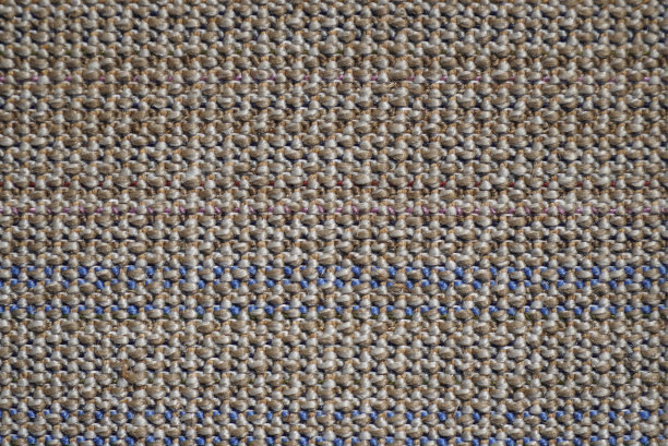 多色地毯的背面，是一块白色的帆布，上面横着一排排蓬松的棕色、米色、粉色和紫色的方形羊毛。图片下载