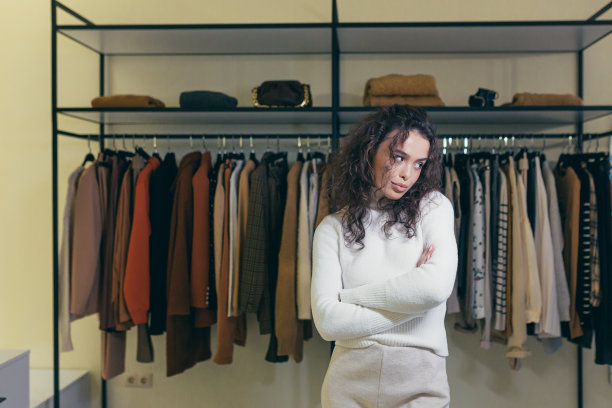 一个沮丧悲伤的年轻女子站在购物中心的一家服装店，双手合十，不满。他在等一个助手，一个顾问。我什么都没买，什么都没选图片下载