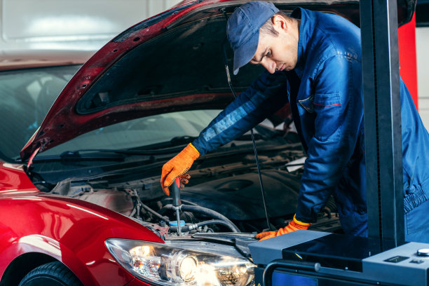 年轻的机械师在汽车服务中调整红色现代汽车的前灯图片下载