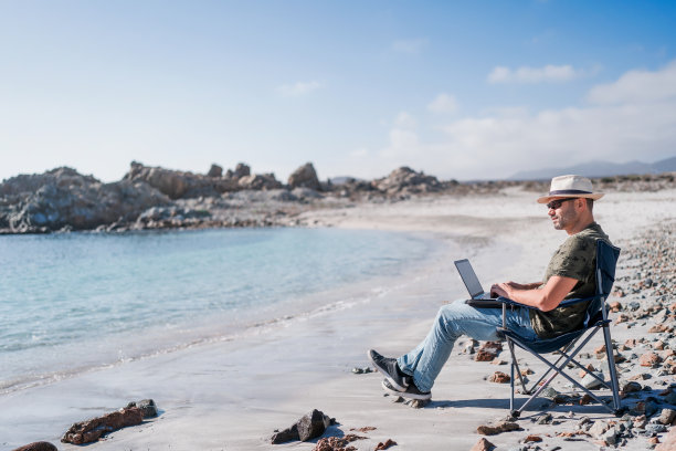 数字游牧民独自坐在沙滩岸边放松工作图片下载