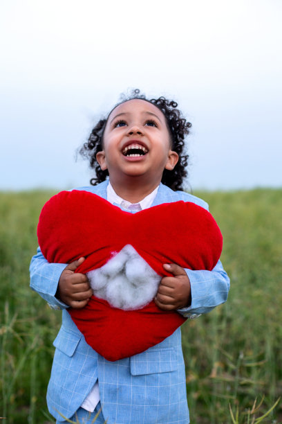 快乐的黑人男孩站在户外，手握一颗撕裂的心图片下载