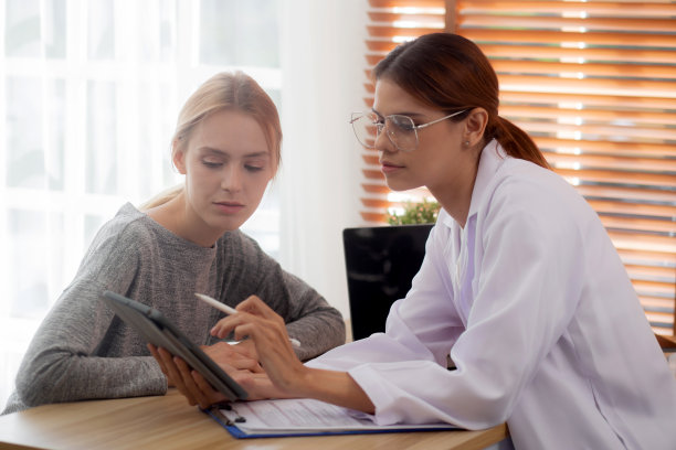 年轻女医生在诊所与患者谈论疾病和疾病诊断，医生解释和咨询疾病和看数码平板，医学概念。图片下载