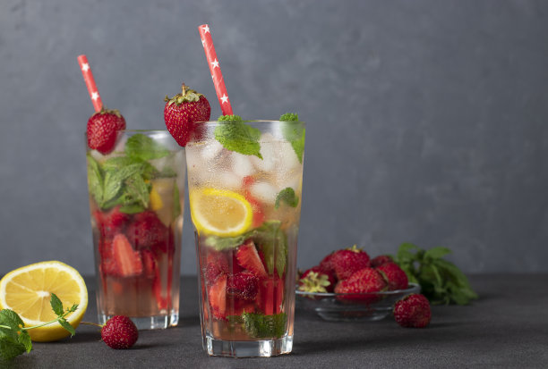 清凉明亮的草莓莫吉托鸡尾酒配上薄荷，柠檬片，冰块和吸管图片下载