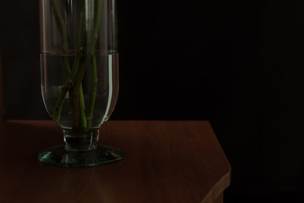 木制桌子上的花瓶的黑色图像，黑色的背景和文字空间图片下载