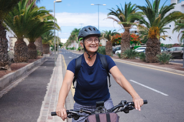 快乐迷人的退休高级妇女与头盔和背包享受体育活动与电动自行车在户外-可持续移动的概念图片下载