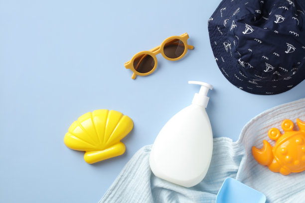 平铺组成防晒乳液瓶，婴儿太阳镜，沙模，巴拿马帽在蓝色的背景图片下载