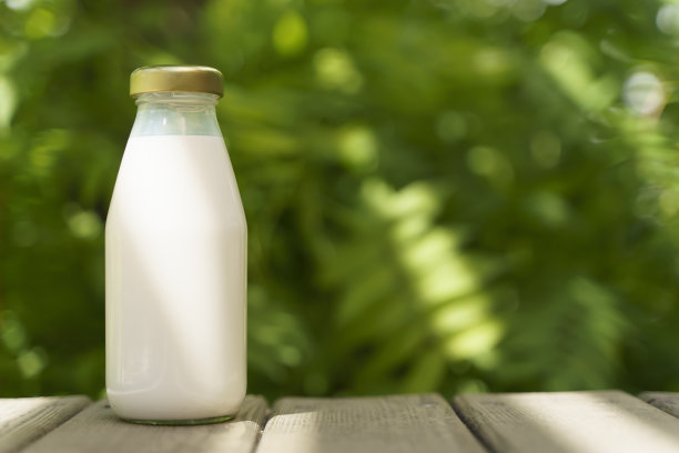 一瓶鲜奶洒在阳光明媚的夏日农场草地上，青草、自然和植物。仿品，生态食品，乳制品概念。图片下载
