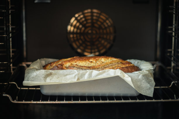 新鲜的香蕉面包在烤箱里准备好了。热的自制糕点在烤盘与羊皮纸的特写图片下载