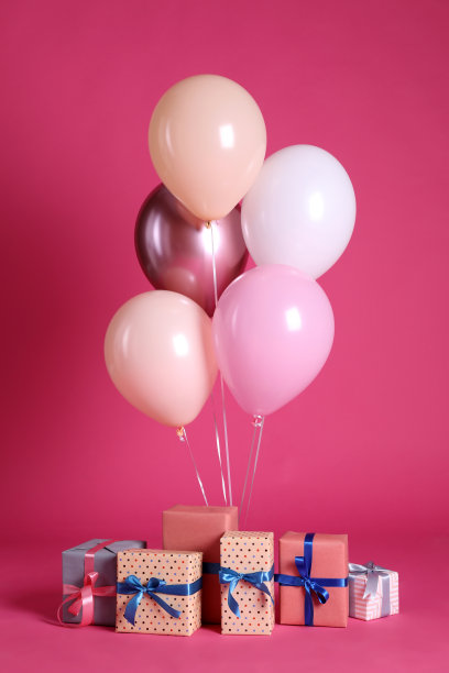 许多礼品盒和气球靠近亮粉色的背景图片下载