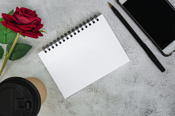 笔记本，一次性咖啡杯，钢笔，智能手机和玫瑰在大理石桌子上。图片下载
