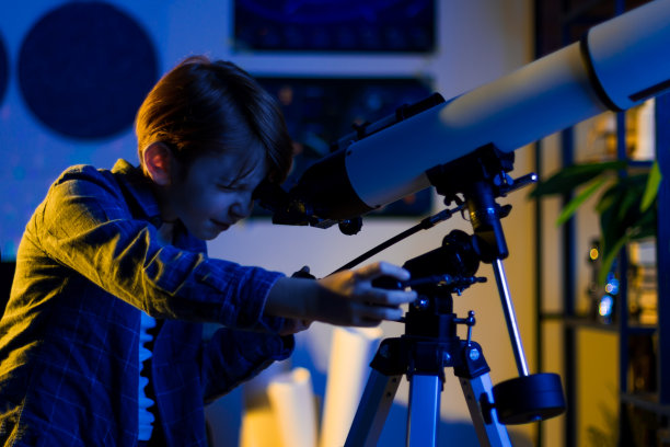 聪明好奇的孩子通过望远镜探索天空。图片下载