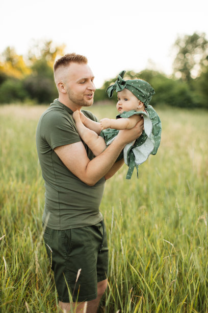 一名年轻男子抱着他六个月大的女婴在操场上散步。图片下载