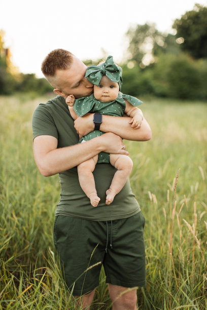 穿着绿色t恤的快乐父亲亲吻小女儿的脸颊的肖像图片下载