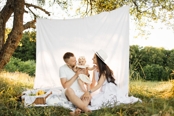 穿着白色衣服的年轻父母和六个月大的女儿在大自然中玩耍的照片图片下载