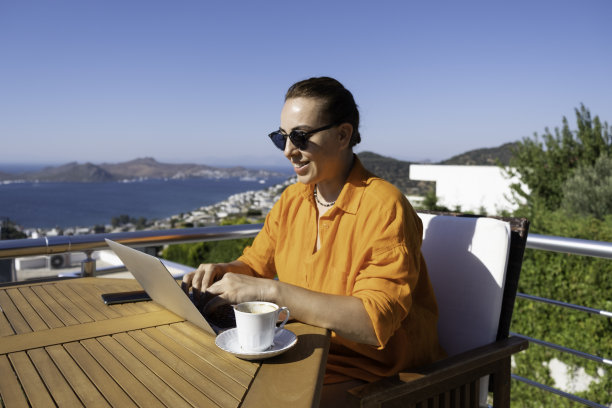 在海上美丽的露台上工作的女人。在家工作。在假期工作。图片下载