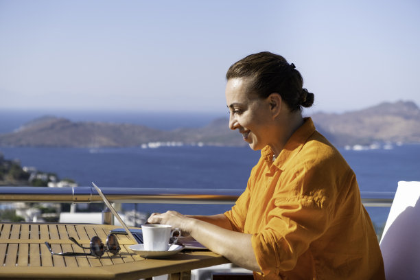在海上美丽的露台上工作的女人。在家工作。在假期工作。图片下载
