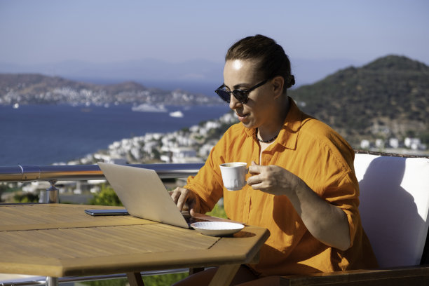 在海上美丽的露台上工作的女人。在家工作。在假期工作。图片下载