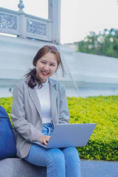 美丽的女生坐在户外的地板上用笔记本电脑学习，在线学习的理念。图片下载