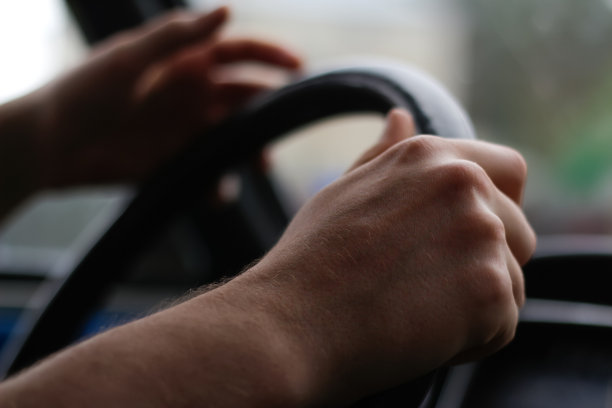 散焦男性手握方向盘。驾驶汽车用的手把方向盘。交通堵塞，在高速公路上开车，在阴天靠近方向盘。的焦点图片下载